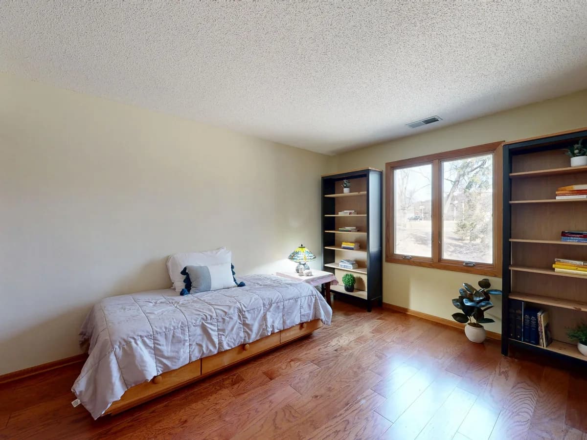 Comfortable, sunlit bedroom with a bed positioned near a window