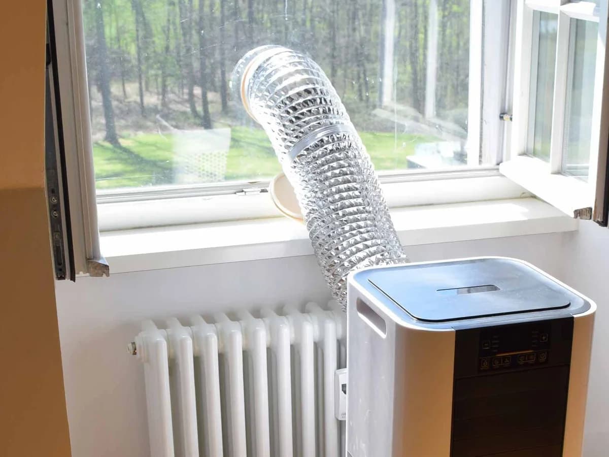 Portable air conditioner with its exhaust hose installed through an open window